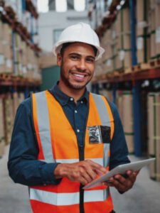 Cheerful young male manager using digital tablet in warehouse